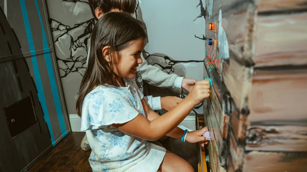 Kids solving a puzzle together during a birthday party escape room at Bond's