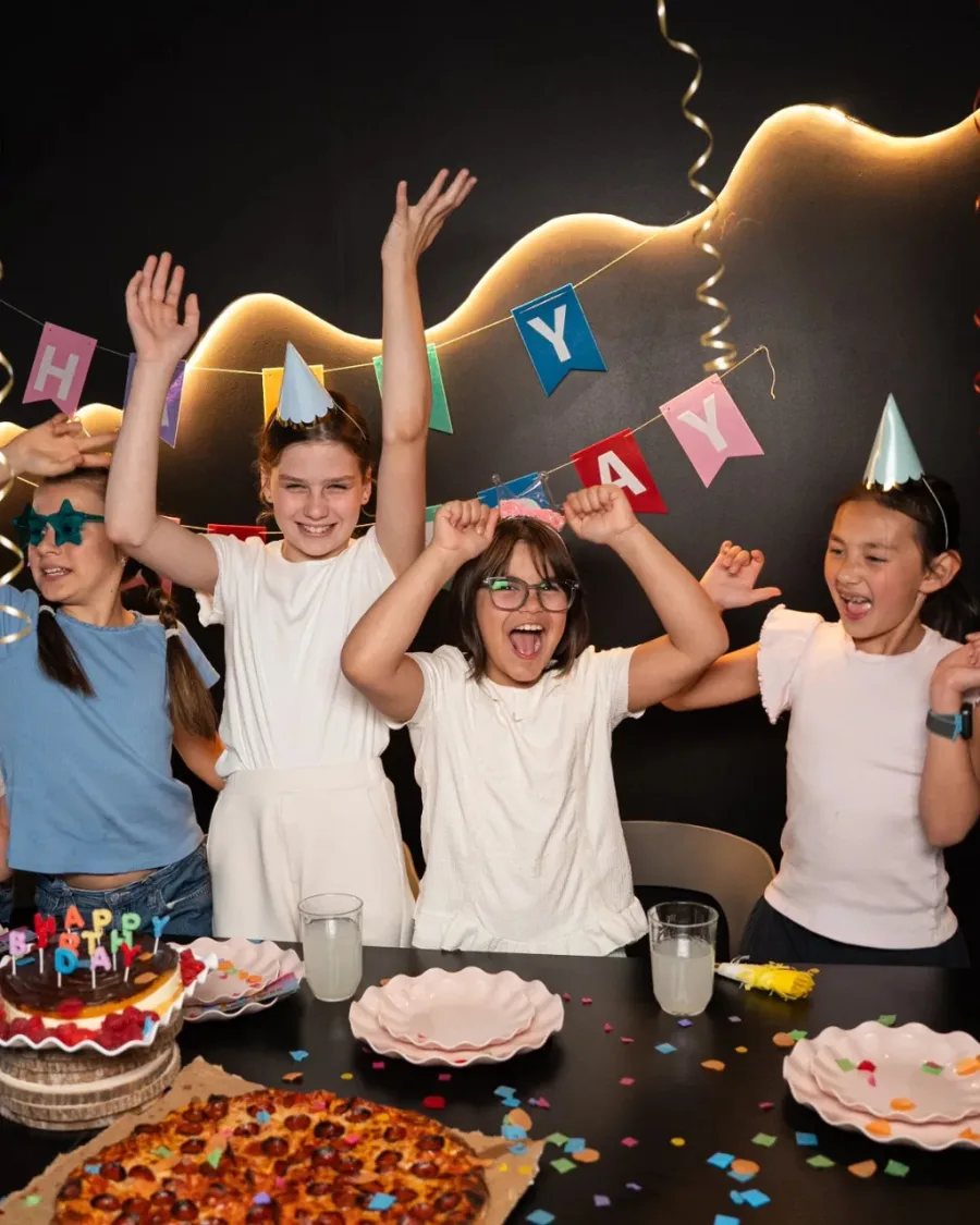 A birthday group cheering with cake and pizza
