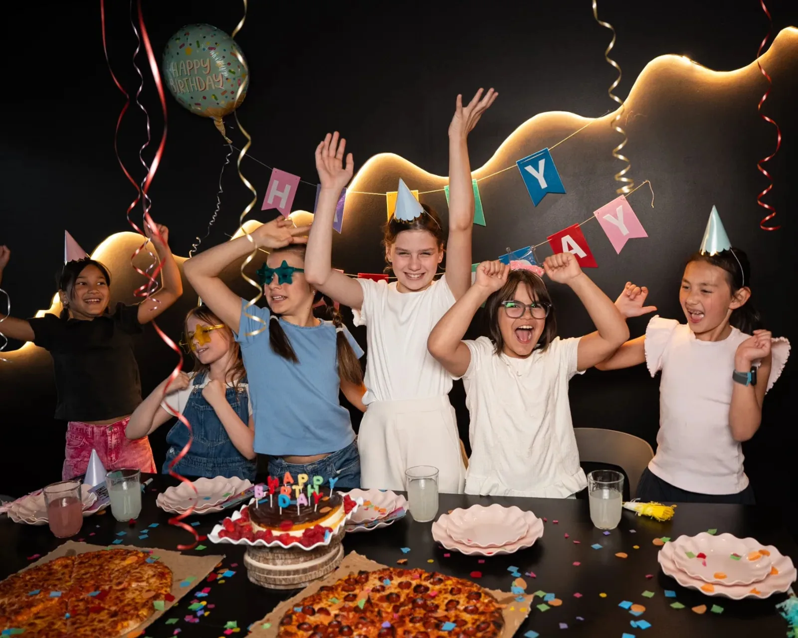 Children cheering around the cake at a birthday party at Bond's