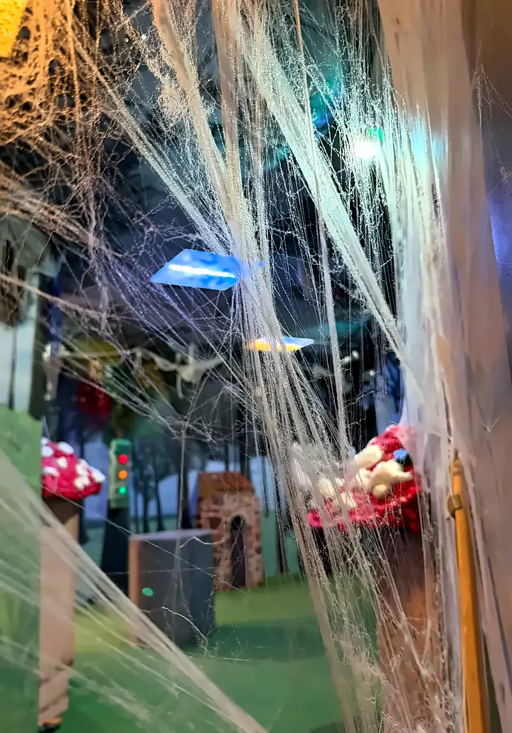 The forest room seen through hanging cobwebs, with giant toadstools and a stone tower in the distance