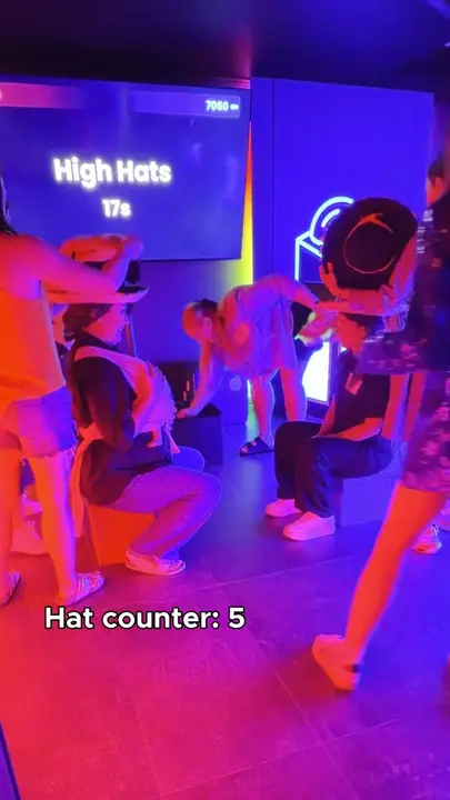 Players crouching in blue and purple light for a hat-stacking challenge, hat counter at 5