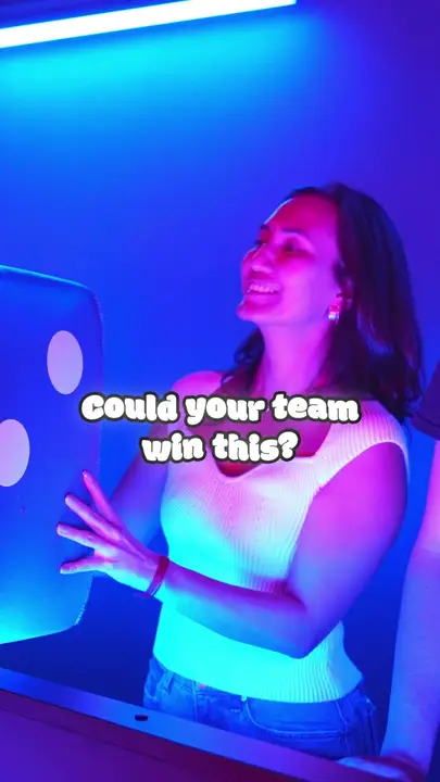 A woman lit in blue asking "Could your team win this?" at the Game Show
