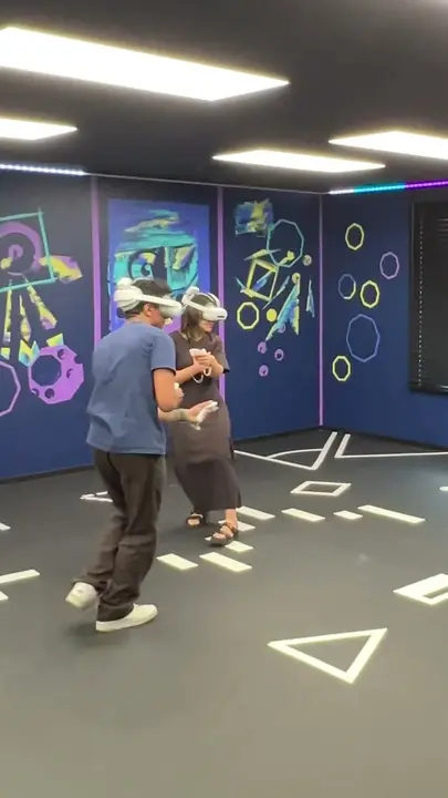 Two players in VR headsets moving around the VR Arena floor
